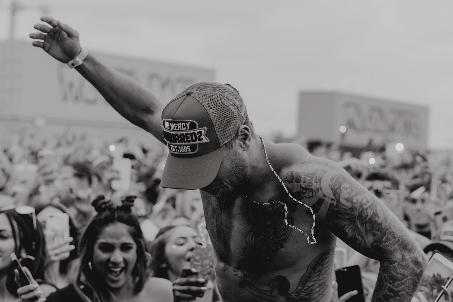 Black and white photo of crowd surfing at music festival with enthusiastic audience.
