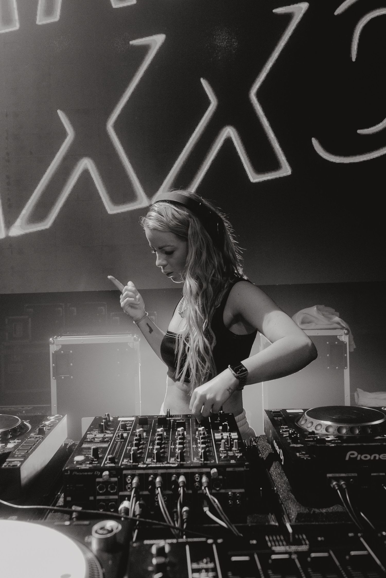 DJ performing on Pioneer equipment in black and white with XXX logo visible in background.