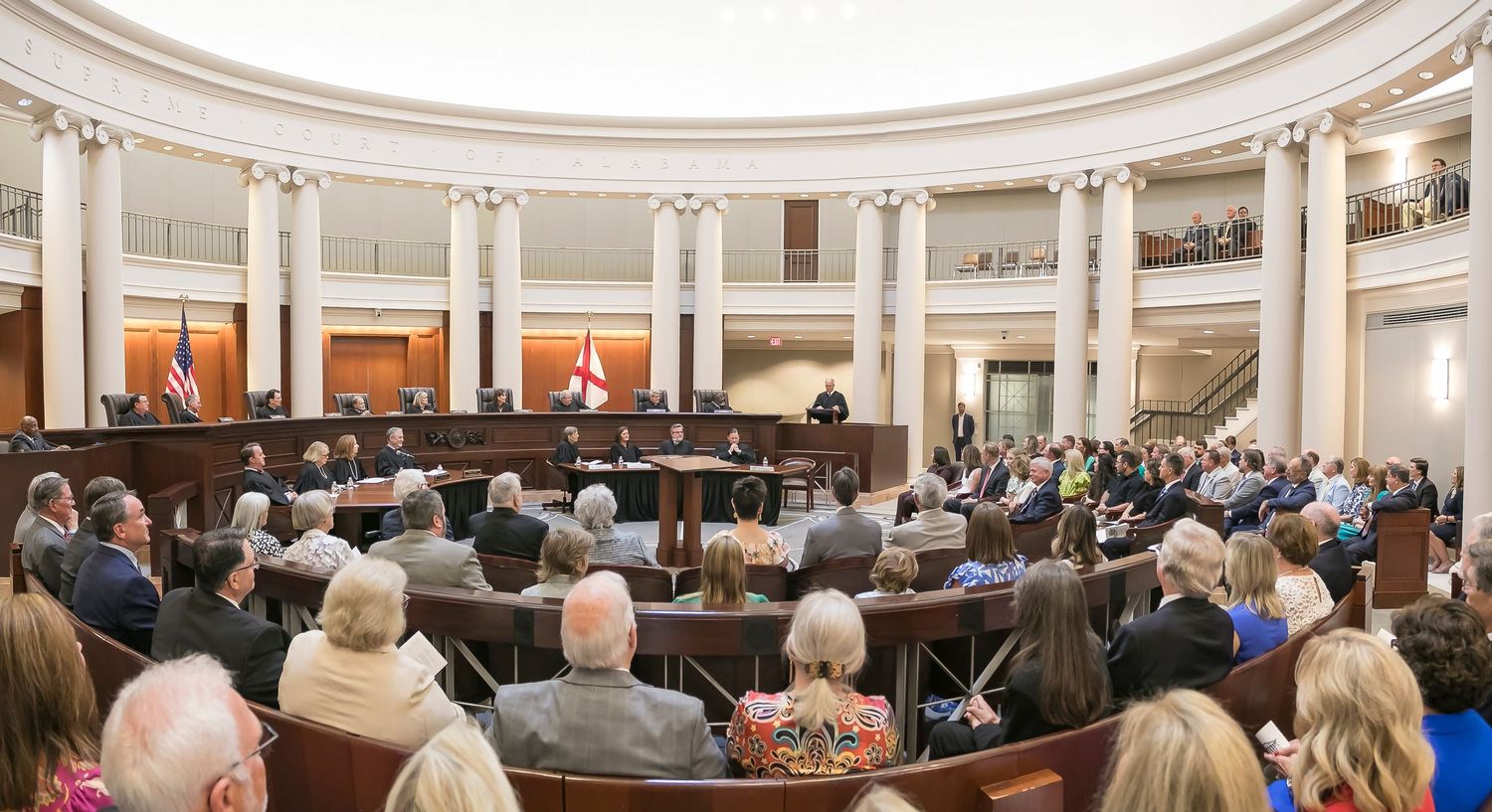A panoramic view of a formal government chamber with white columns and a curved gallery filled with attendees.