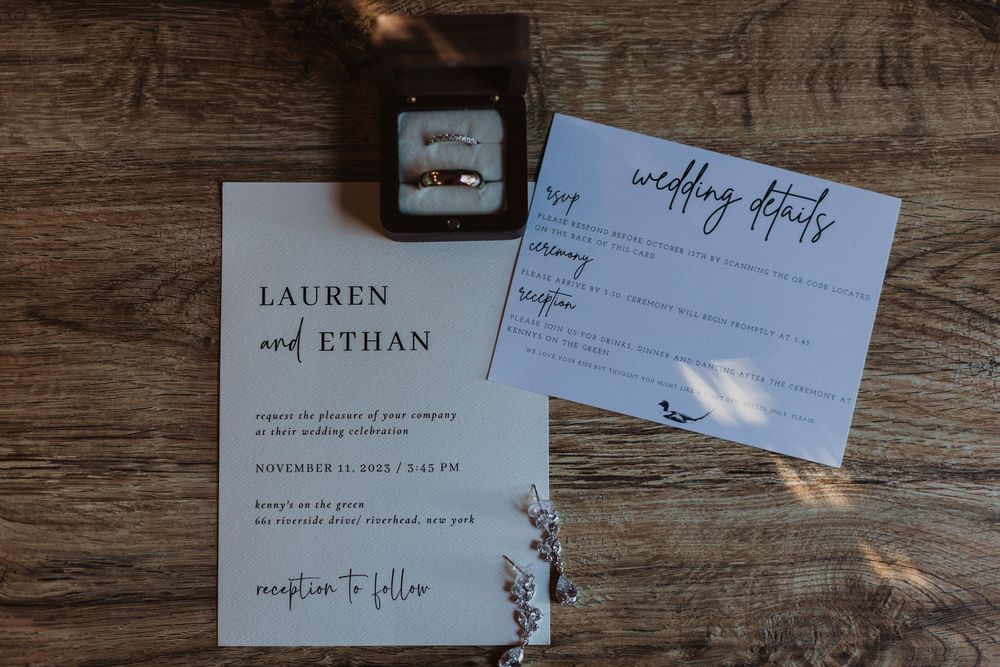 Wedding invitation suite with elegant calligraphy displayed on rustic wooden surface in muted tones.
