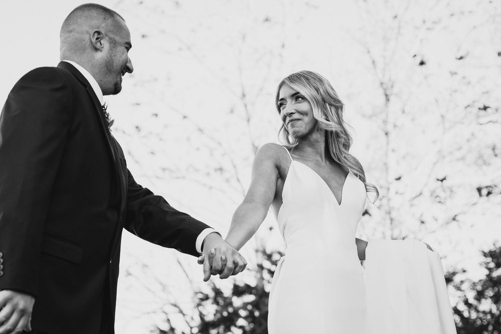 A couple shares an intimate moment during their black and white outdoor wedding celebration.