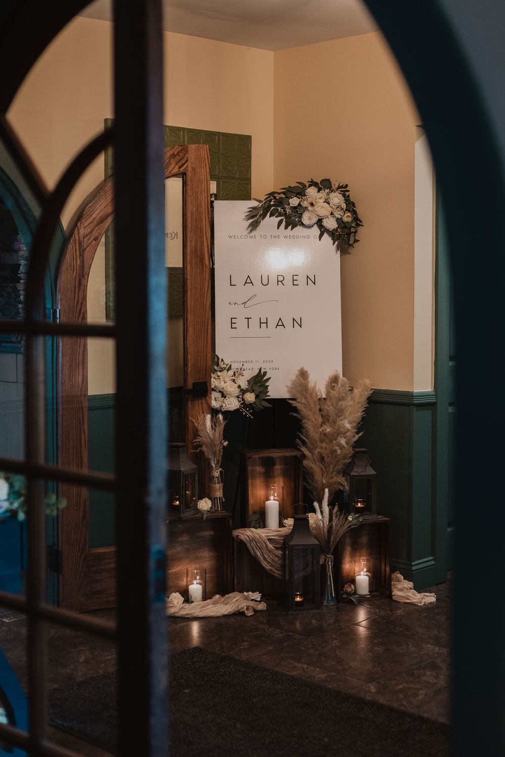 Wedding reception decor features candlelit window displays with elegant white floral arrangements and name cards.