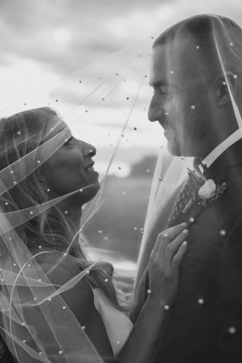 A romantic black and white wedding photo sequence showing a couple embracing under a flowing veil in soft lighting.