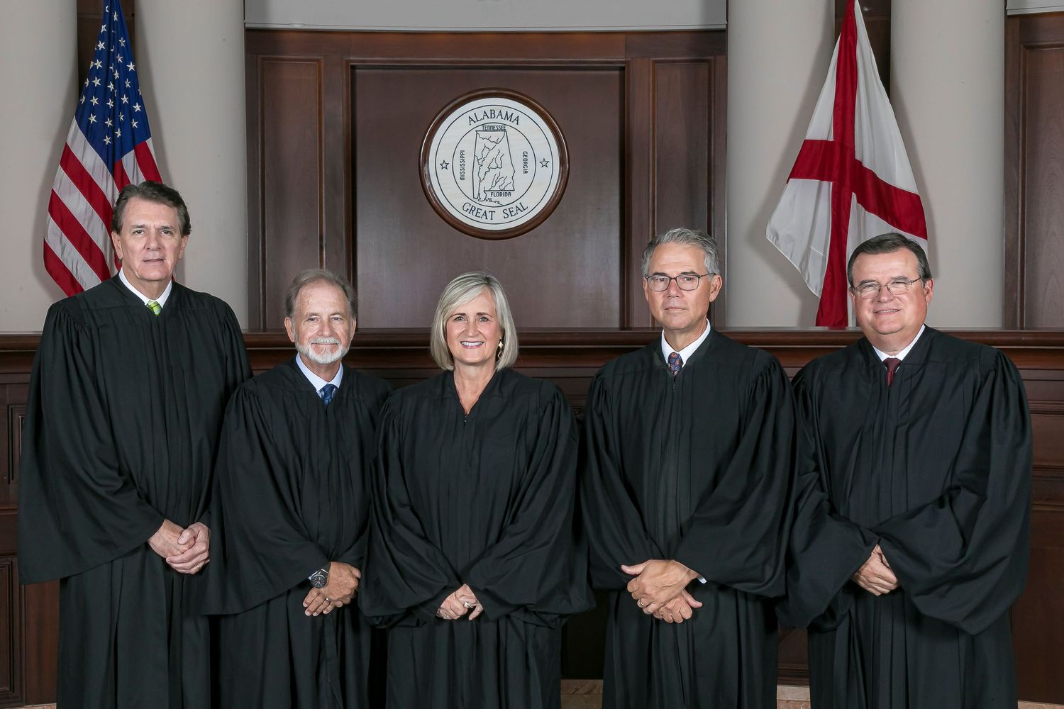 Supreme Court justices in black robes seated for official group photo in wood-paneled courtroom.
