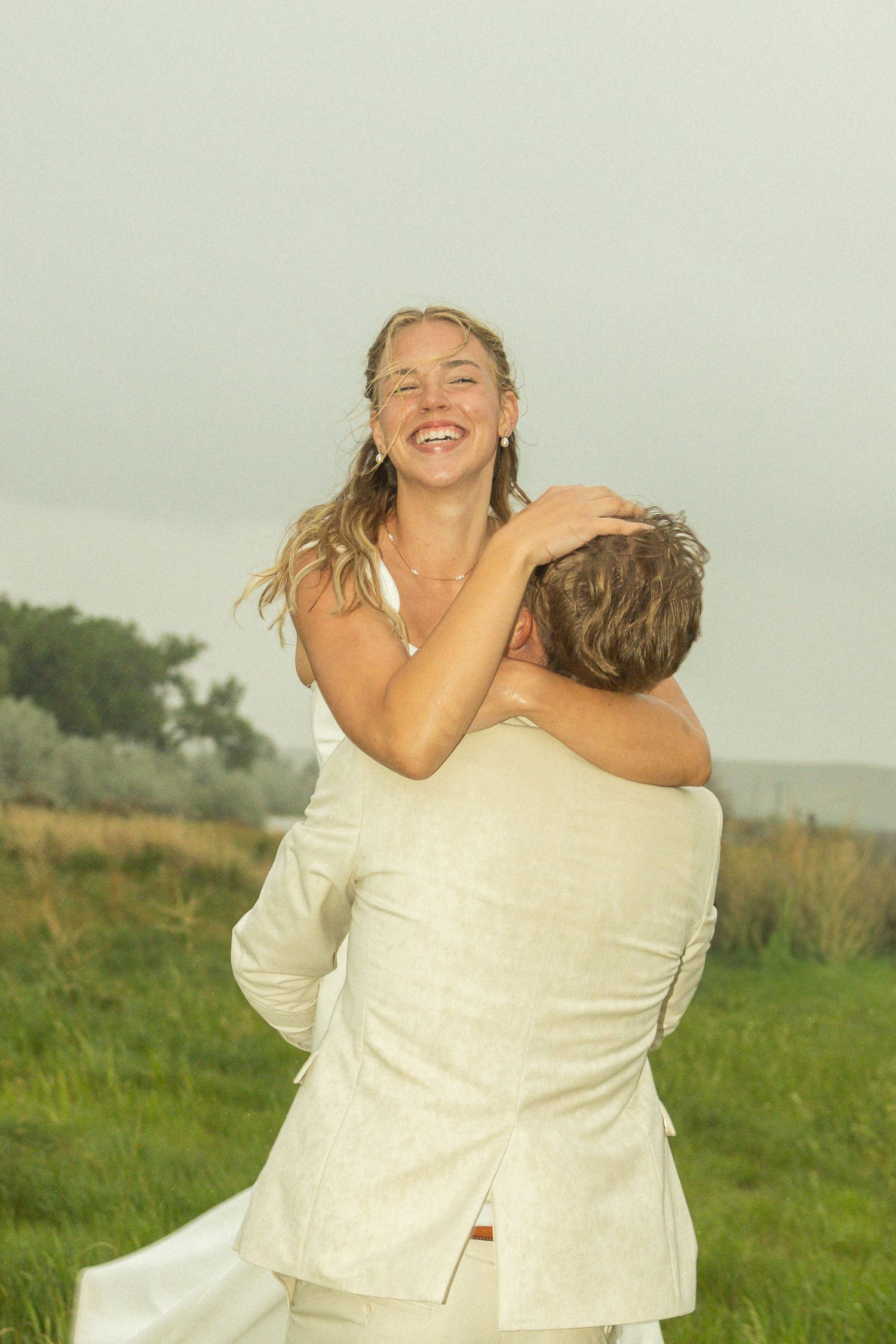 A romantic sequence of wedding photos showing a couple kissing under a flowing veil in a sunlit outdoor field.