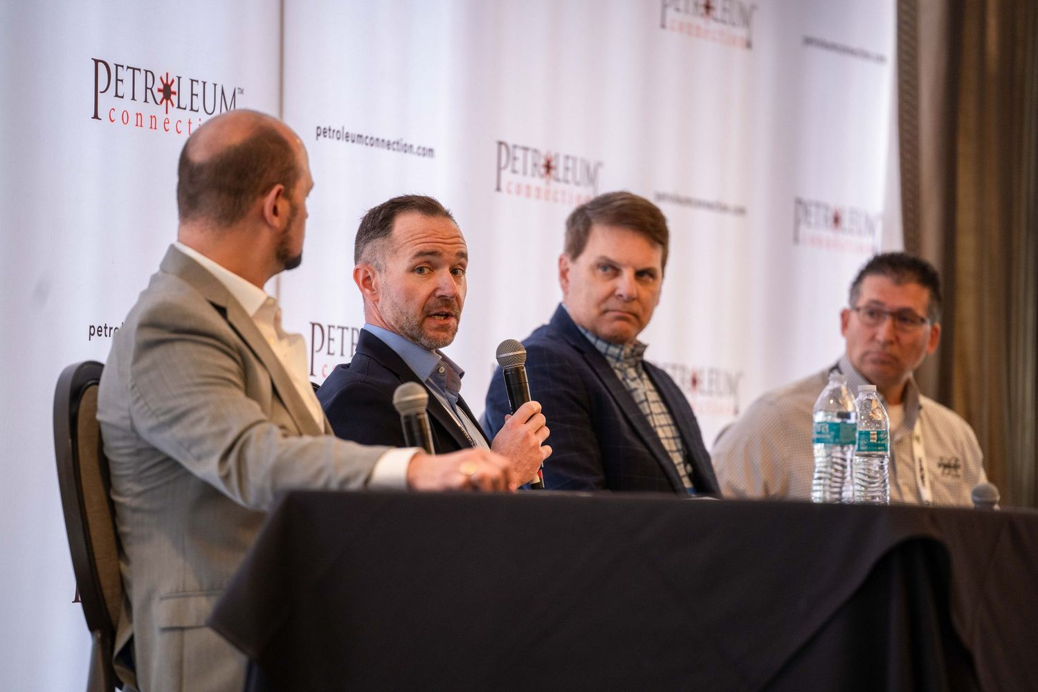 Panel discussion setup with speakers seated at a table in front of a branded backdrop.