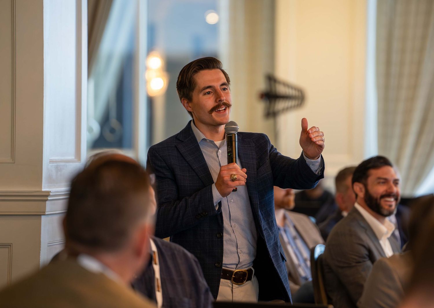 Business professionals engaged in discussion during a conference panel in a brightly lit meeting room.