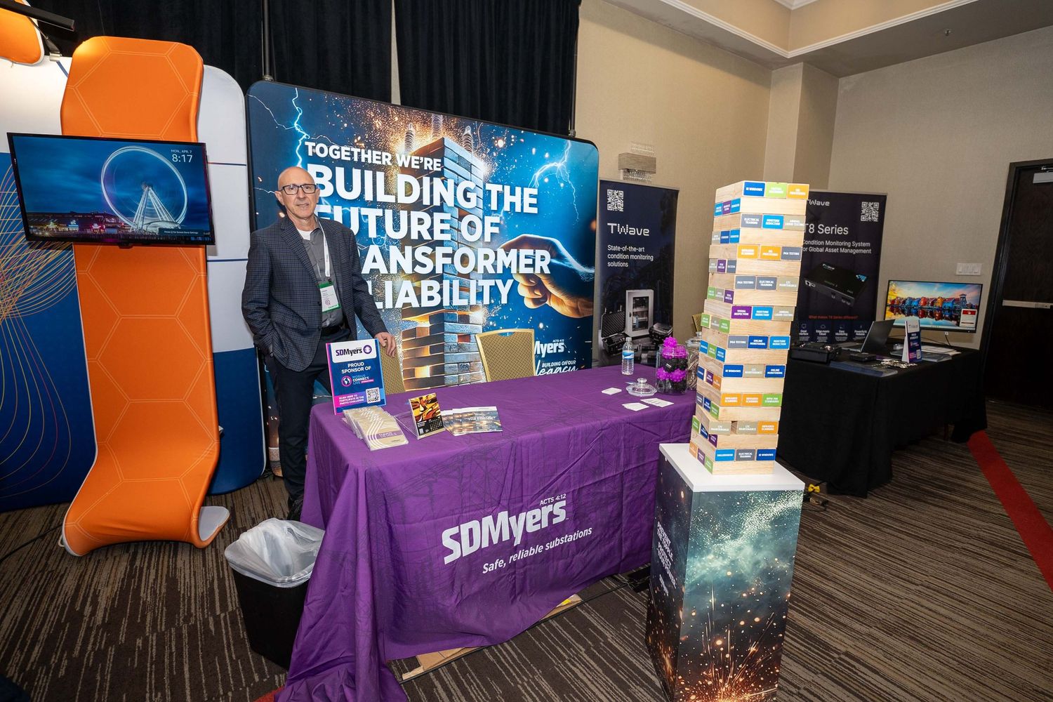 Conference exhibitors display purple and orange branded banners at tech event booths with promotional materials.