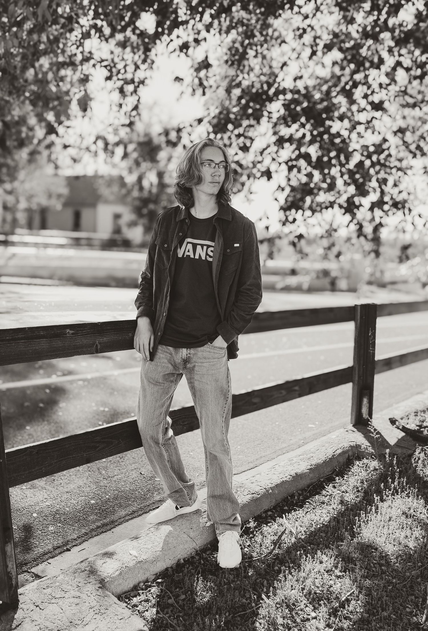 Black and white photo series showing someone in jeans and jacket sitting on a wooden fence in a park setting.