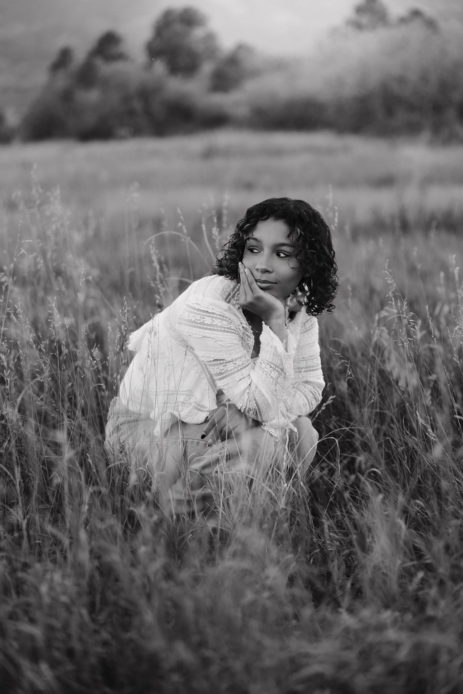 A series of artistic black and white portraits taken in a grassy meadow showing ethereal poses.