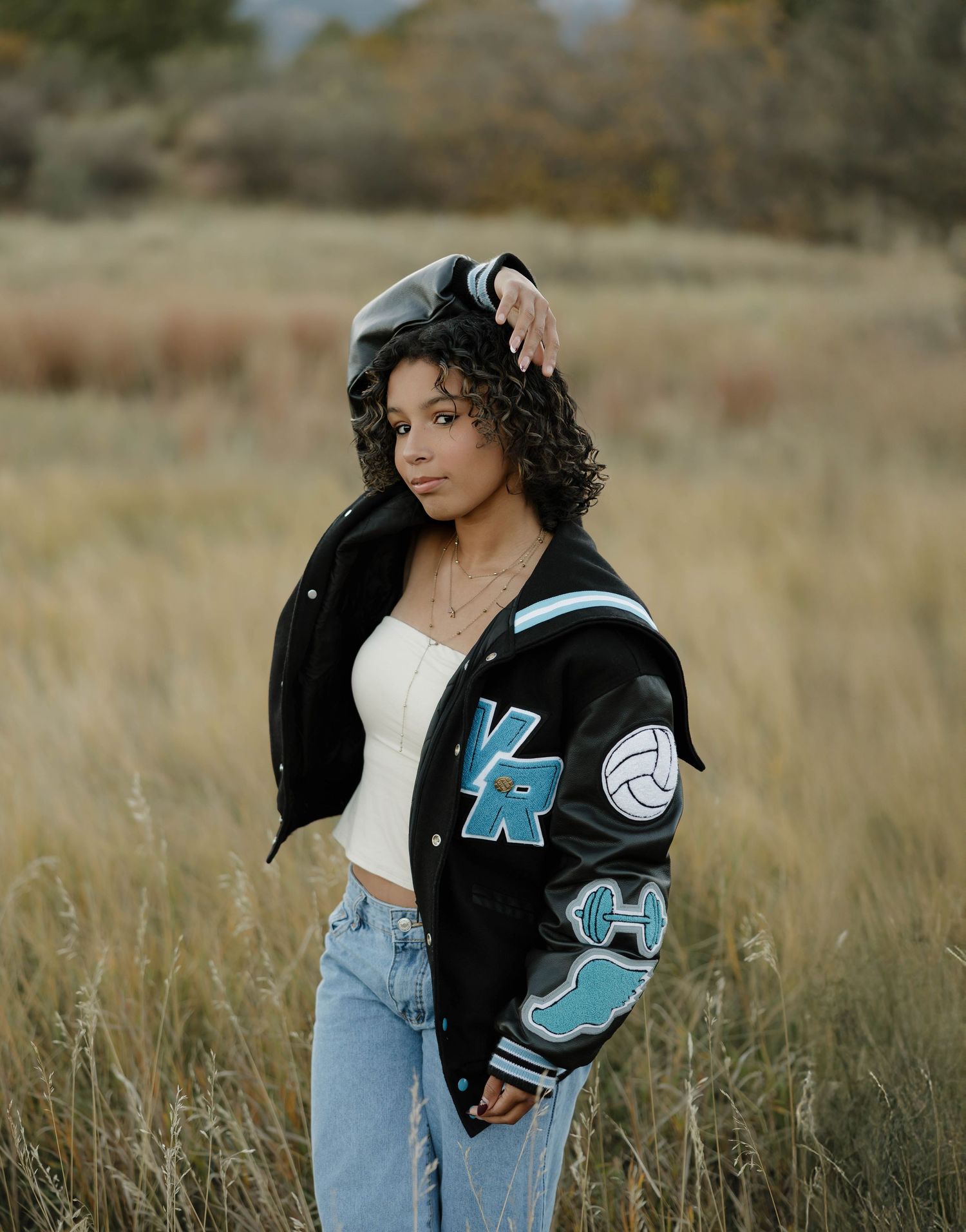 A series of outdoor fashion portraits featuring a varsity jacket and casual denim in golden field lighting.