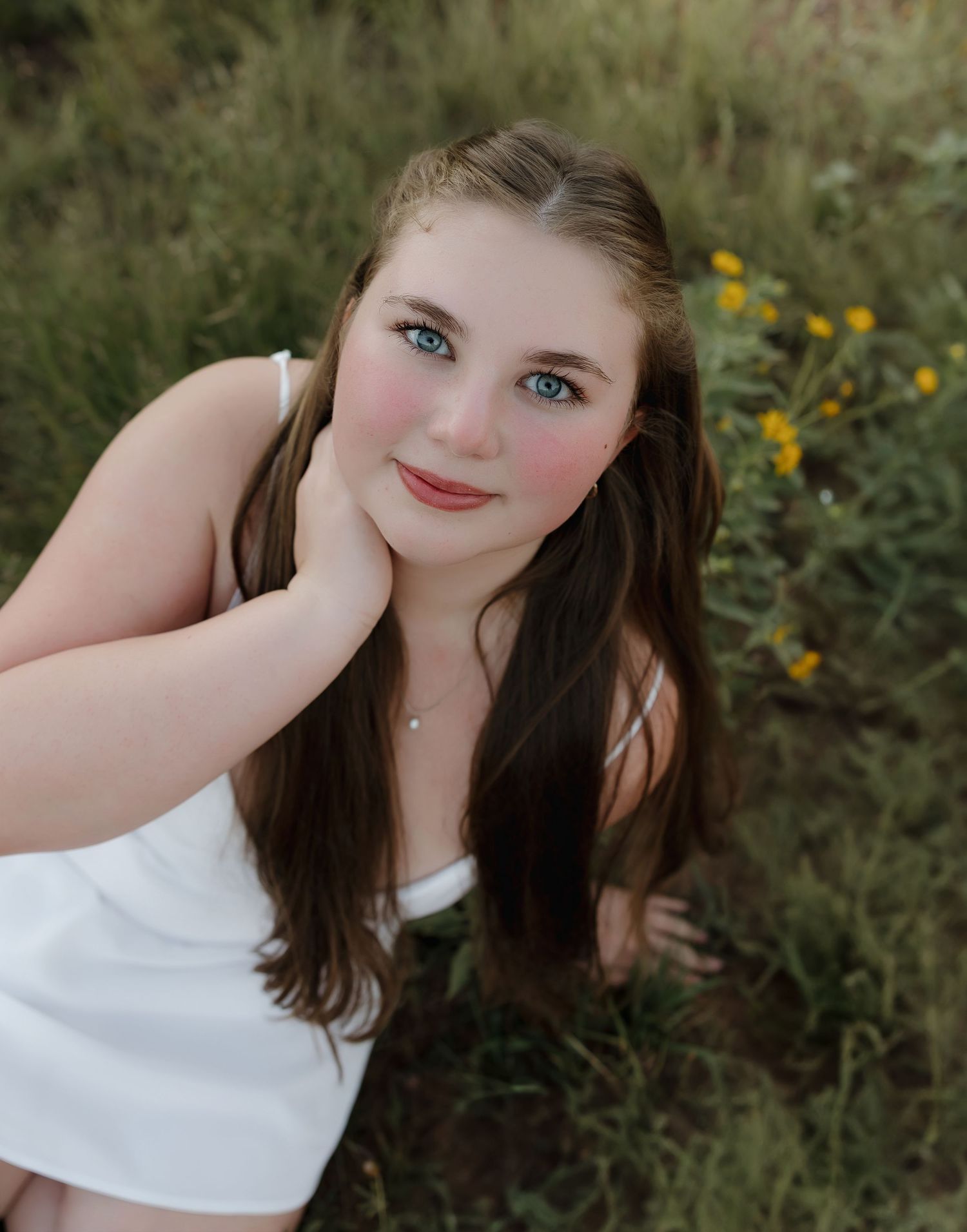 Artistic portrait shot in a wildflower meadow with natural lighting and white clothing.
