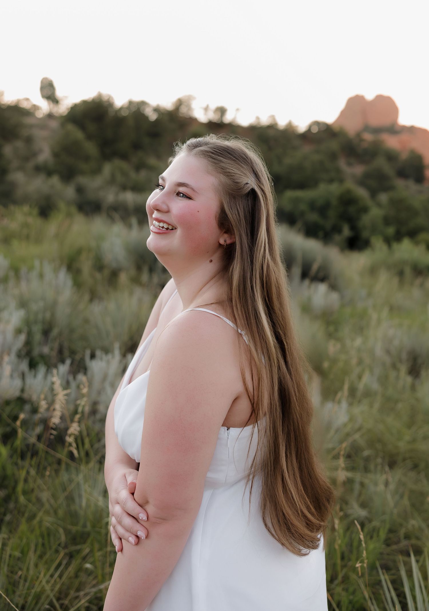 Outdoor portrait session featuring a white sundress against a natural backdrop of mountains and desert vegetation.