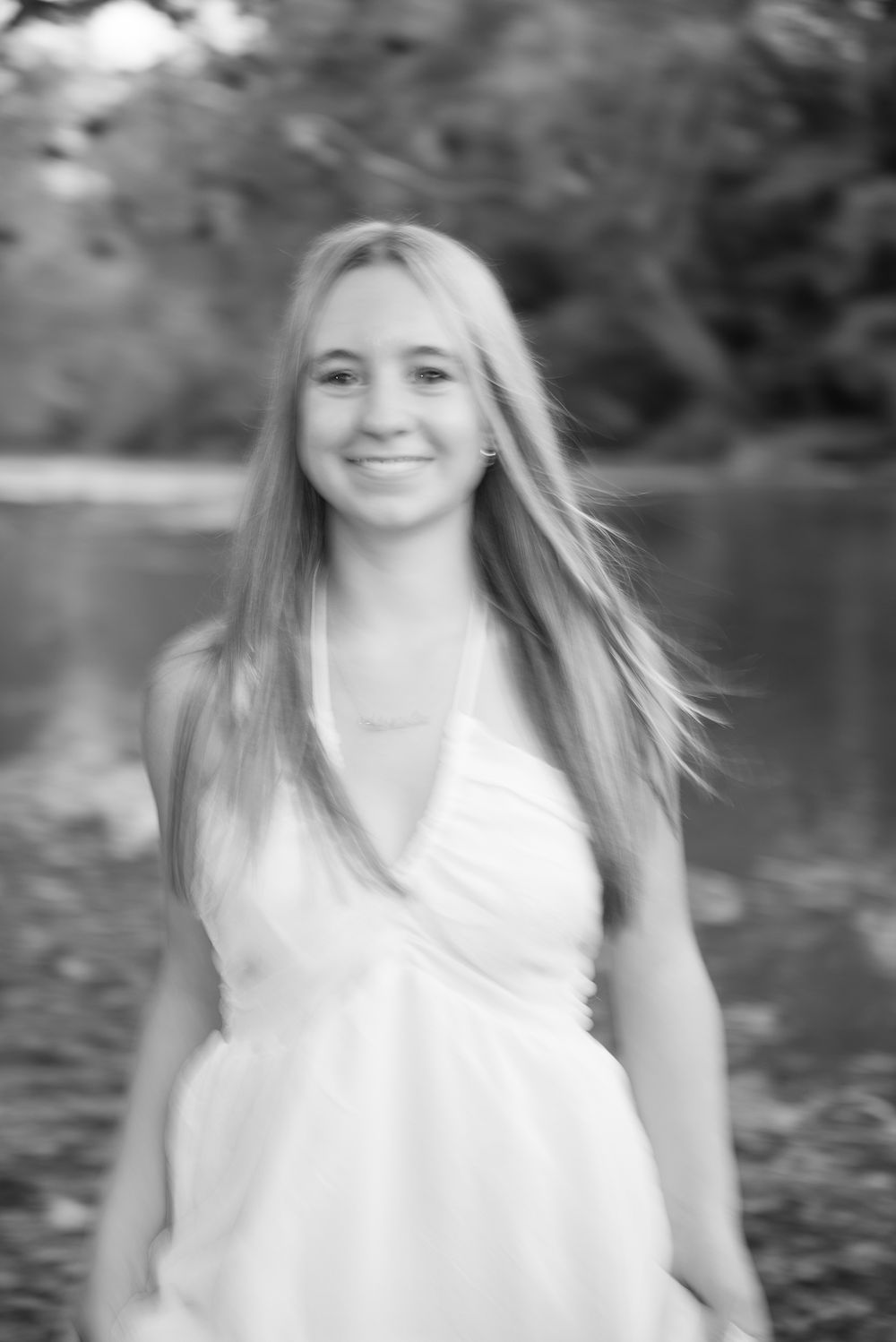 Black and white portrait photograph showing a person in a white top with long hair against a blurred background.