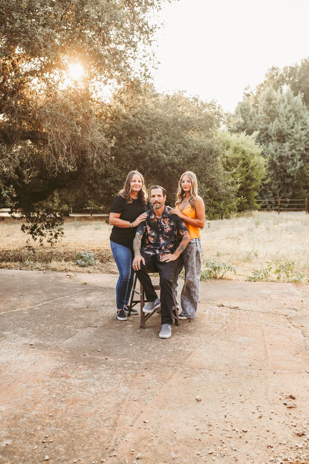 A warm sunset photoshoot in a park with three people posing together on a paved path.