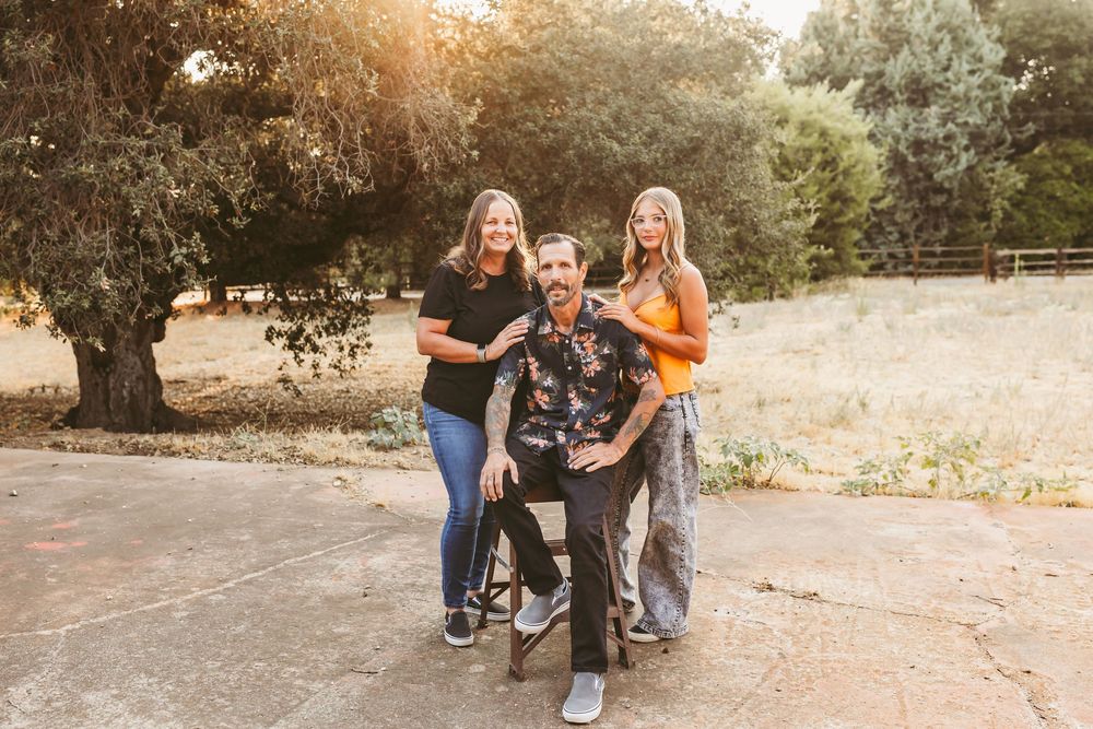 A group sits together on a rustic stone wall during golden hour at sunset in an outdoor setting.