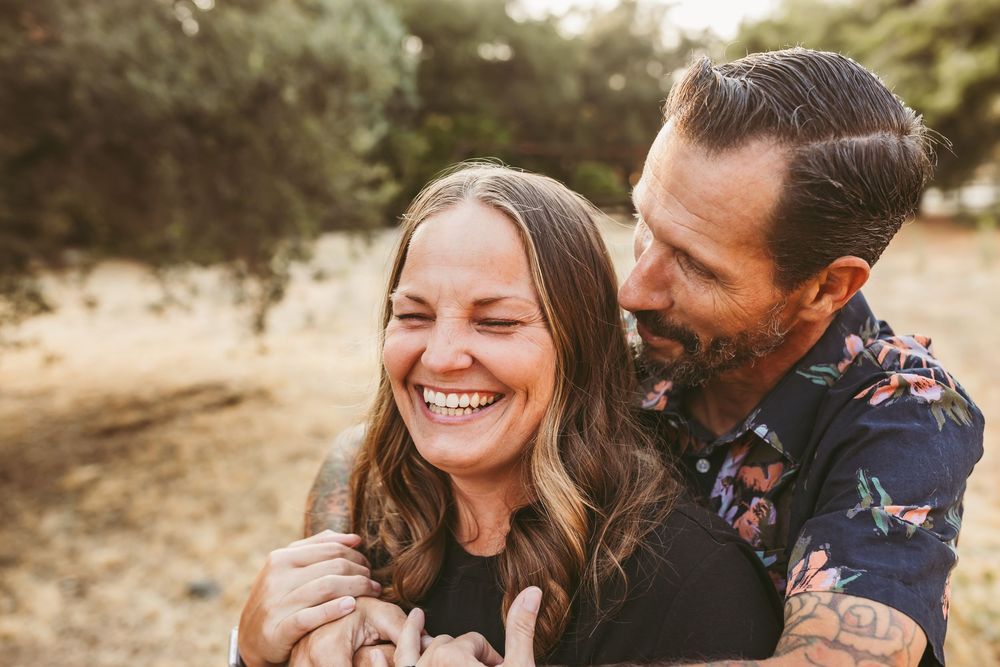 A couple shares intimate moments outdoors in a series of candid photos showing natural laughter and affection.