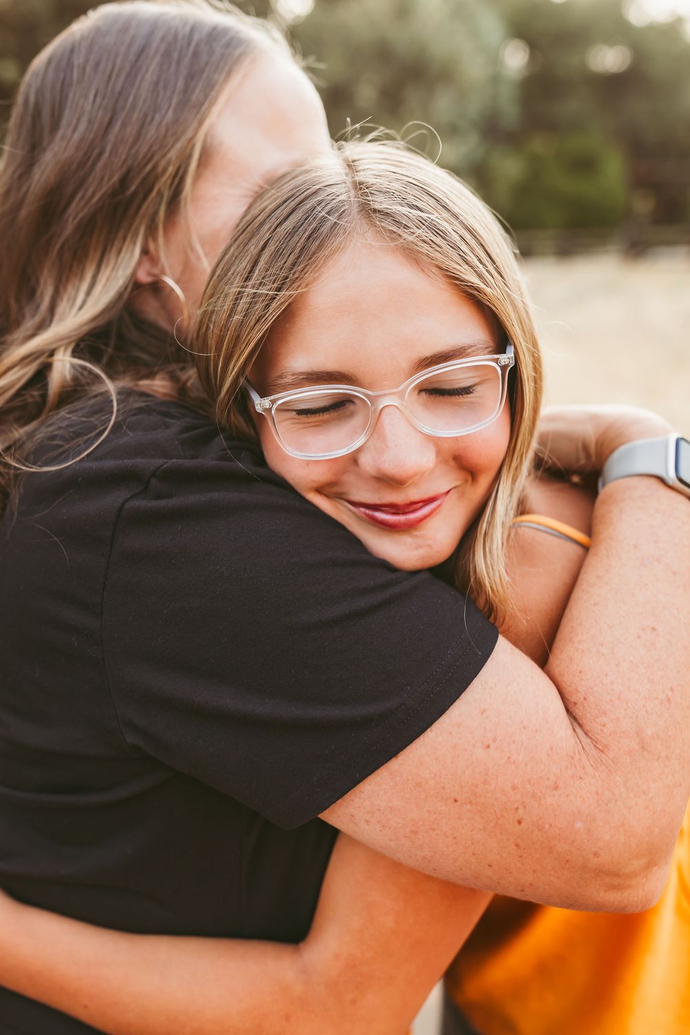 A warm embrace between two people wearing glasses is captured in a series of intimate close-up photos at sunset.