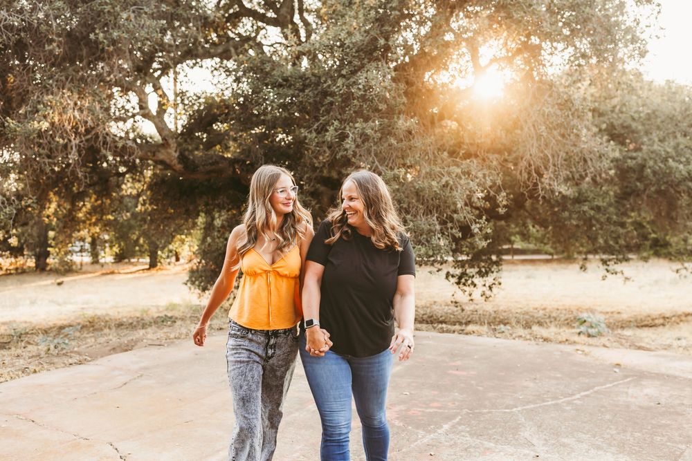 Couple holding hands while walking on a dirt path during golden hour sunset.