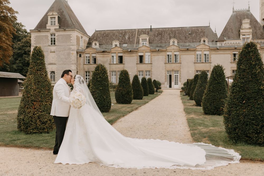 Romantic wedding photoshoot in front of a majestic stone chateau with manicured gardens.
