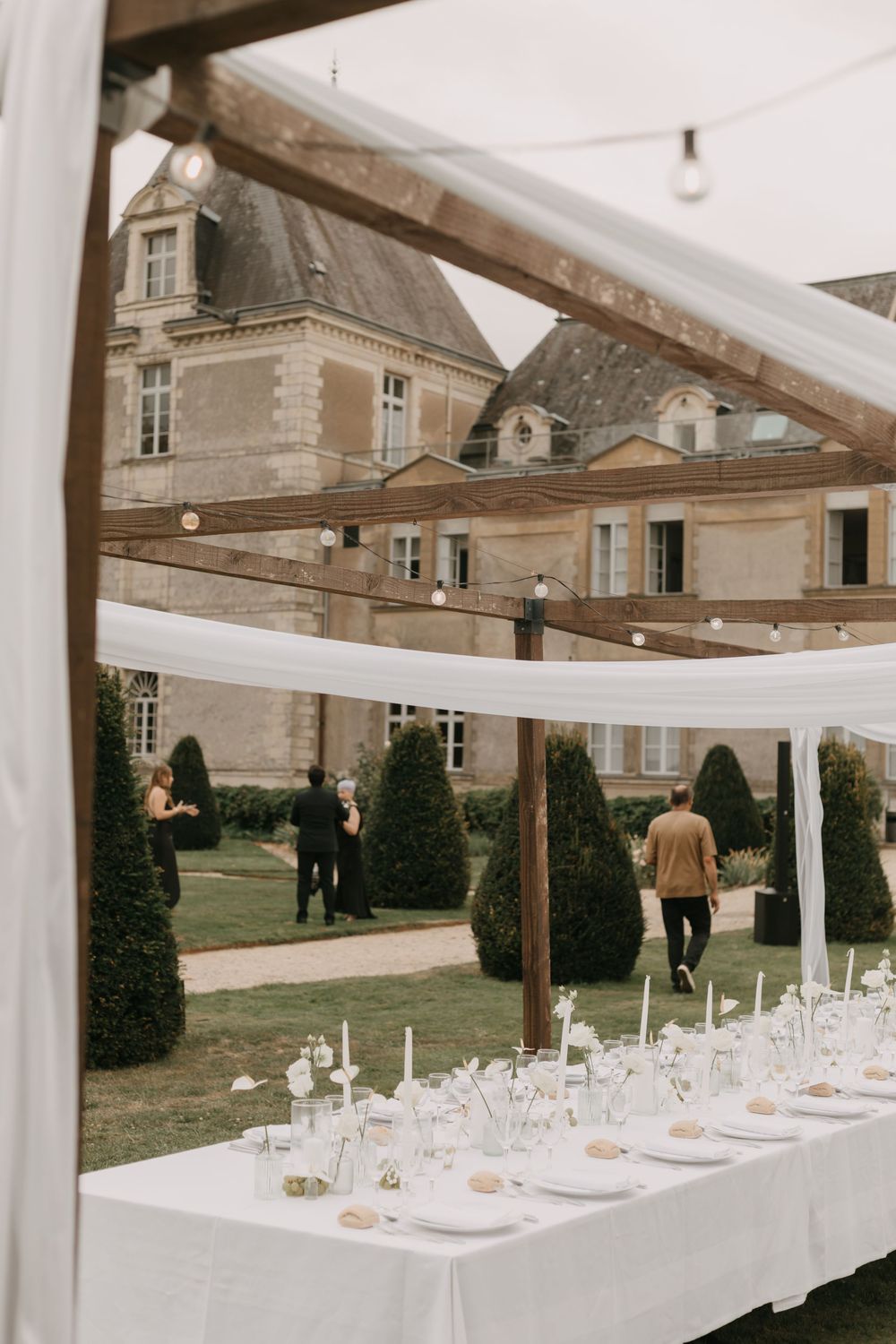 Elegant outdoor wedding reception setup with white tent and formal table settings.