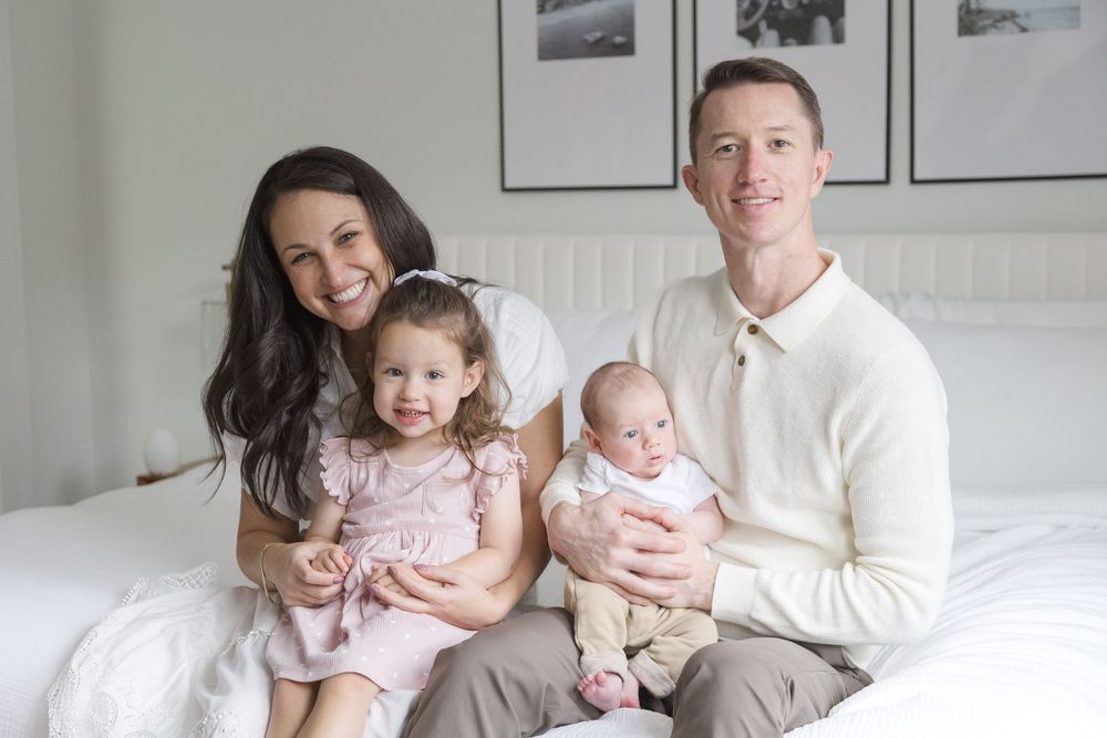 "Smiling family with newborn and cute smiling toddler during in-home lifestyle photo session in Glover Park, Washington DC."