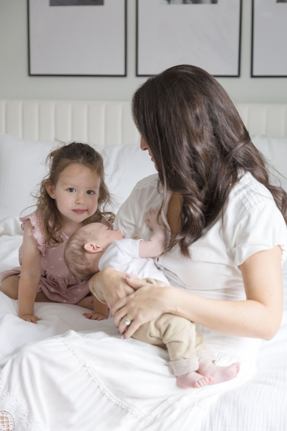 "Beautiful mother holding newborn baby boy with toddler smiling at the camera in elegant in-home newborn session in Washington DC."