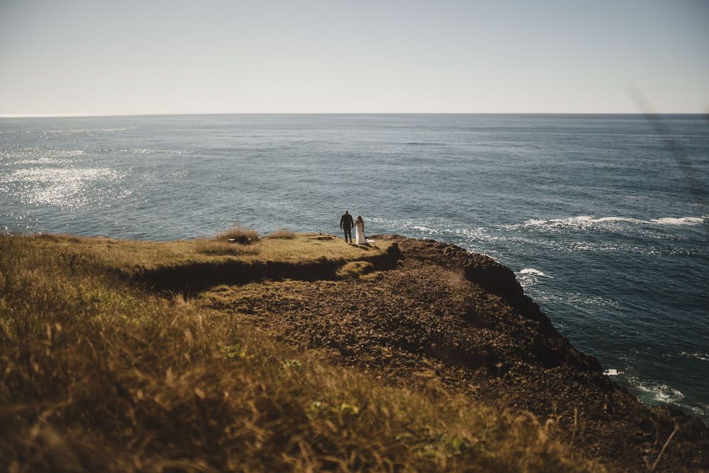 A scenic coastal trail along rugged cliffs overlooking the vast Pacific Ocean on a cloudy day.