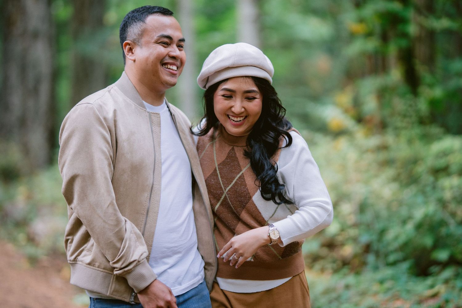 A couple shares joyful moments together in a lush green forest setting during their engagement photo session.