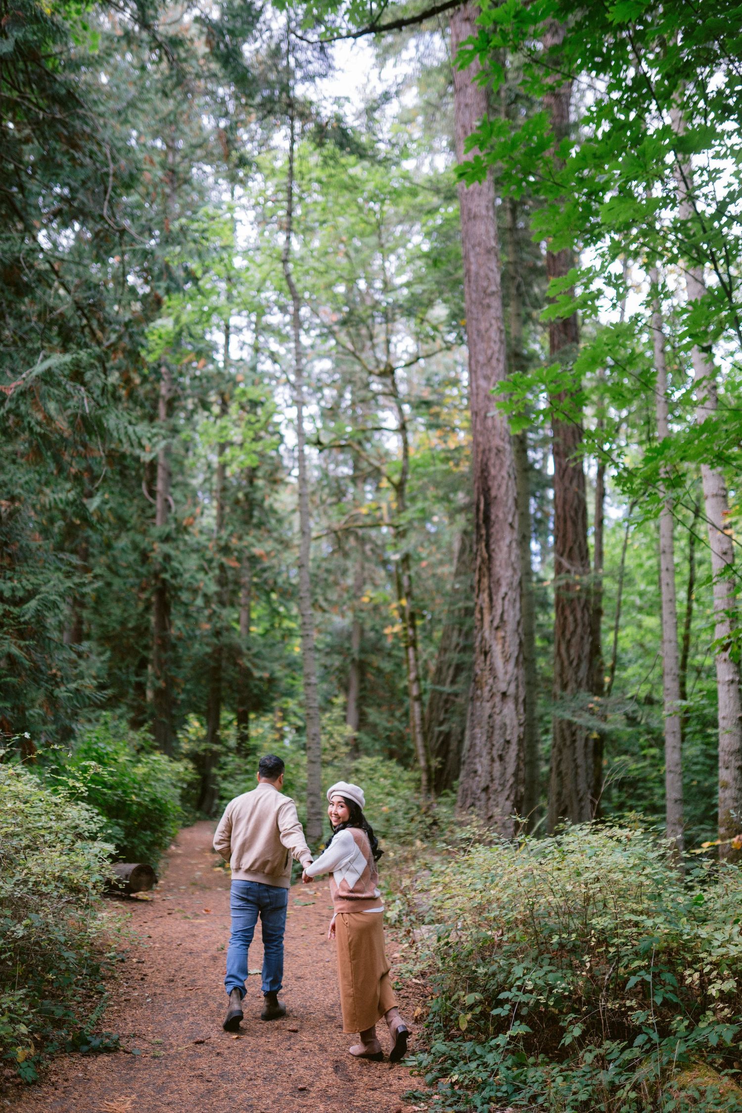 Romantic forest photoshoot with tall evergreen trees creating a natural backdrop.