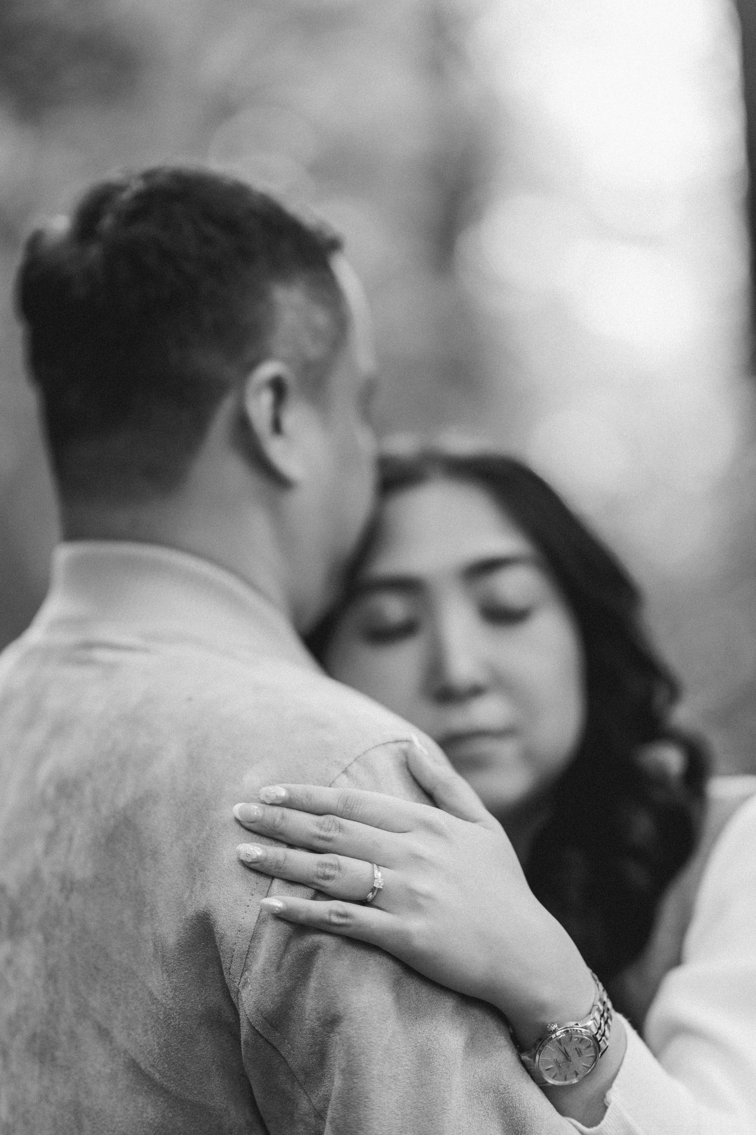 A tender black and white photo sequence shows a couple embracing, with focus on the woman's hand resting on her partner's back.