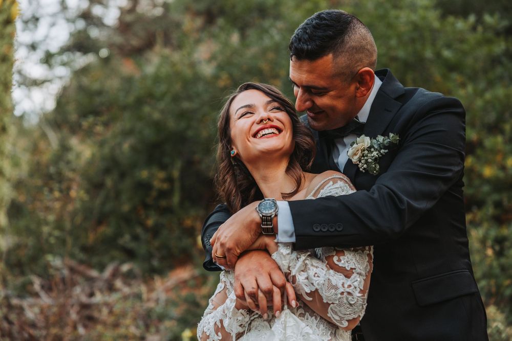 A joyful couple embraces and laughs together during their outdoor wedding photoshoot.