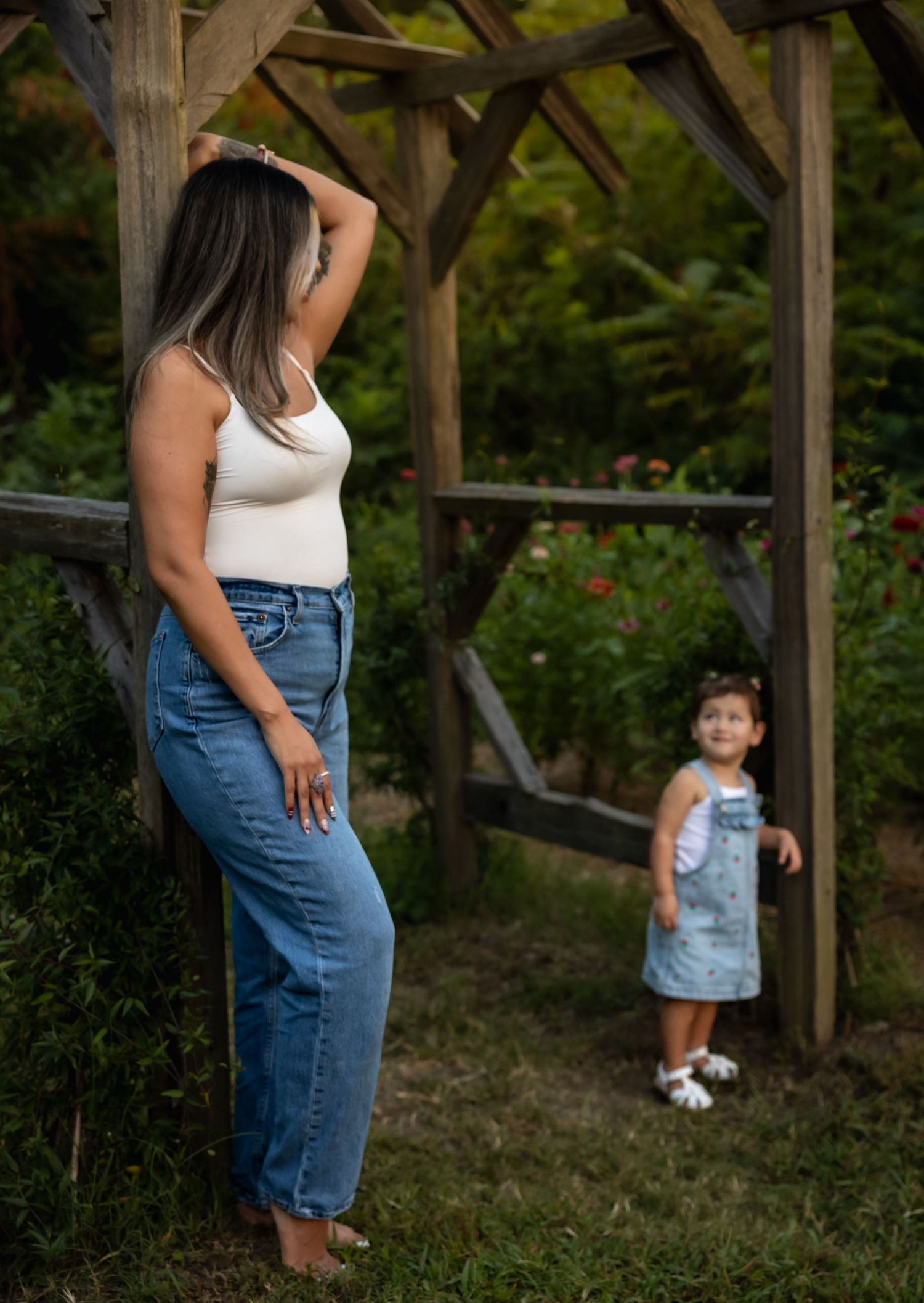 Mother and child playing together under a wooden pergola in a garden setting.
