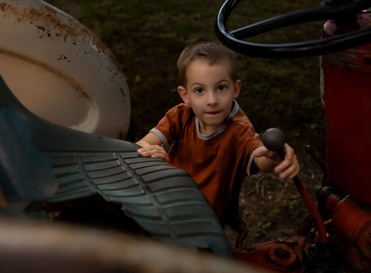 Child playing with steering wheel in moody lighting.