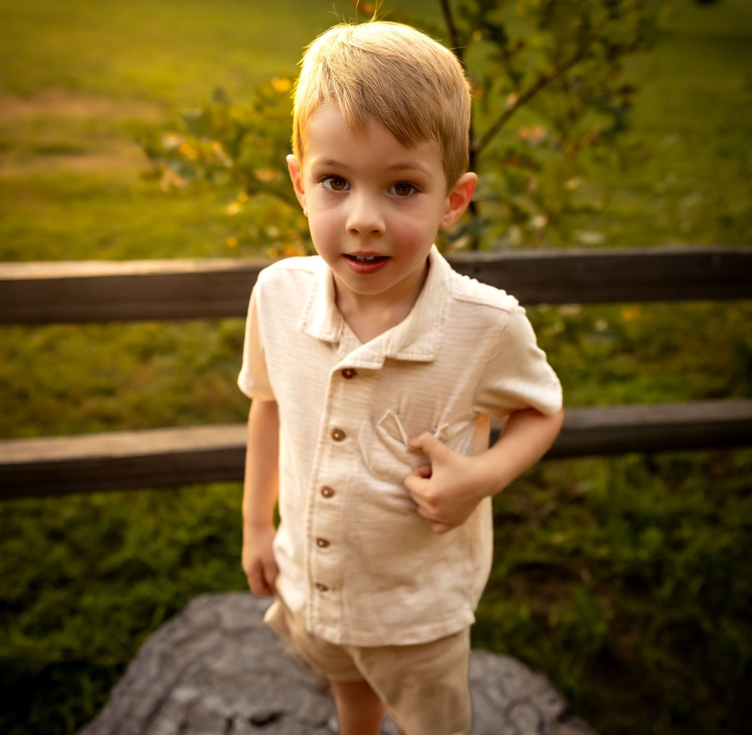 Child wearing light colored shirt plays on outdoor surface in natural setting.