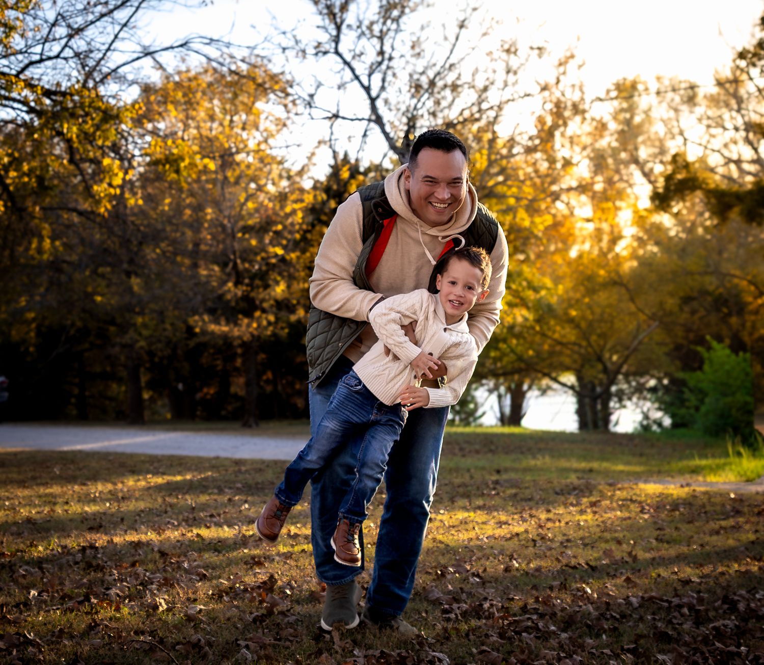 Two people share a playful moment outdoors during golden hour in an autumn park setting.