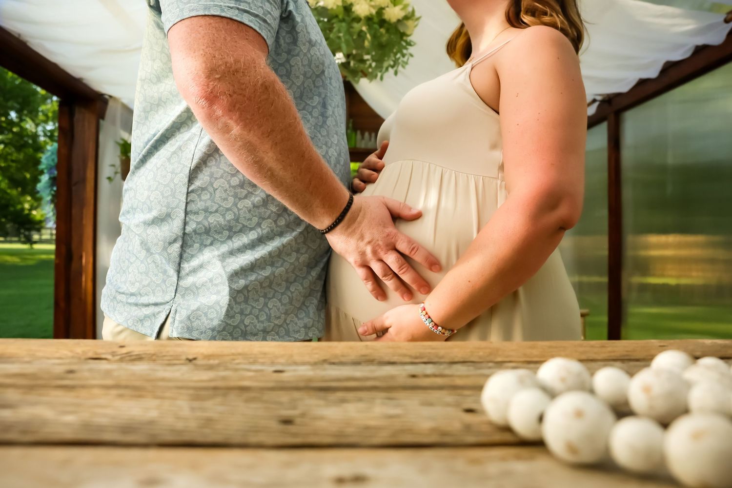 Maternity photoshoot with parents gathered at rustic wooden table with decorative elements.