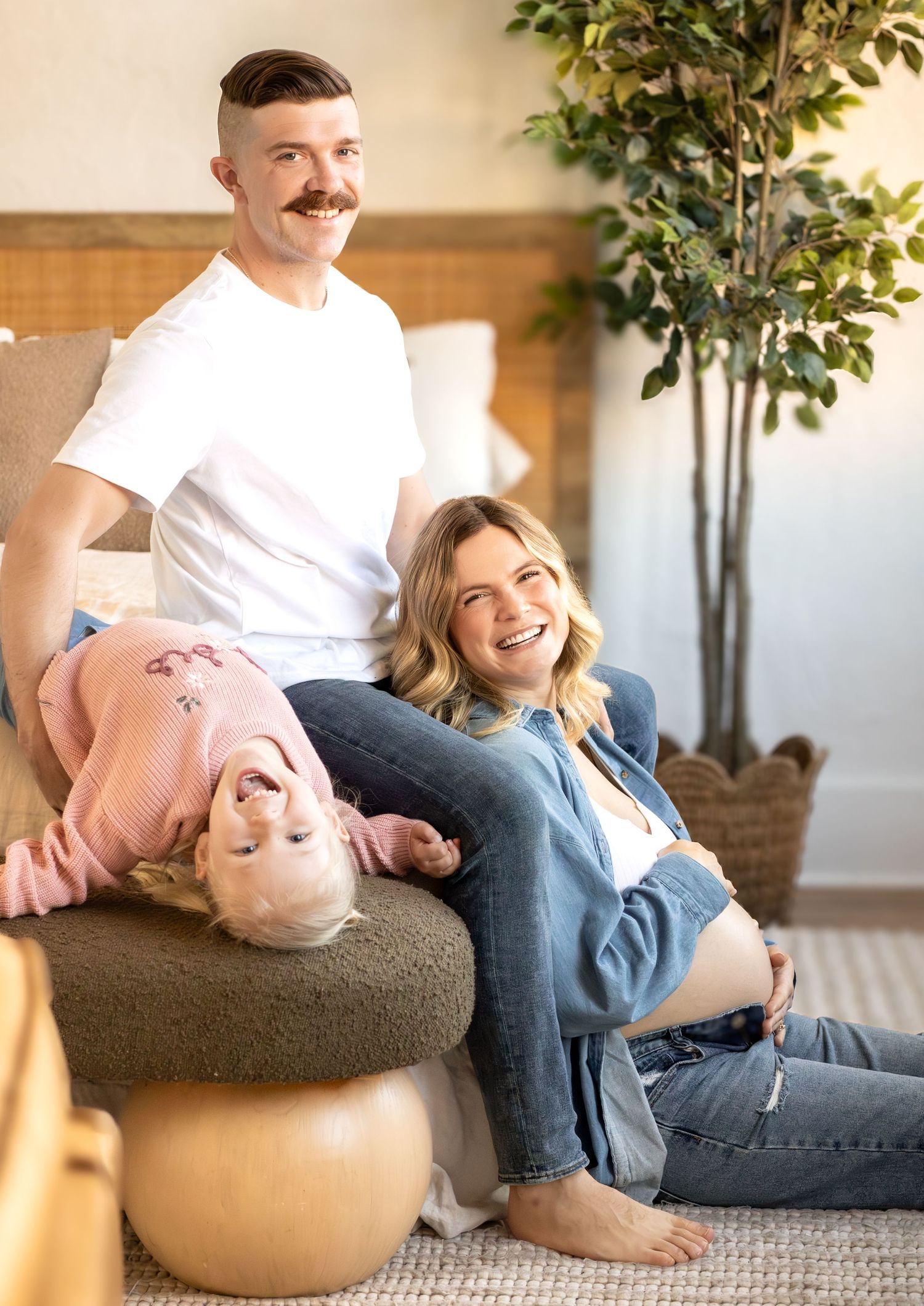 Couple relaxing and laughing together on an exercise ball in a bright living room with plants.