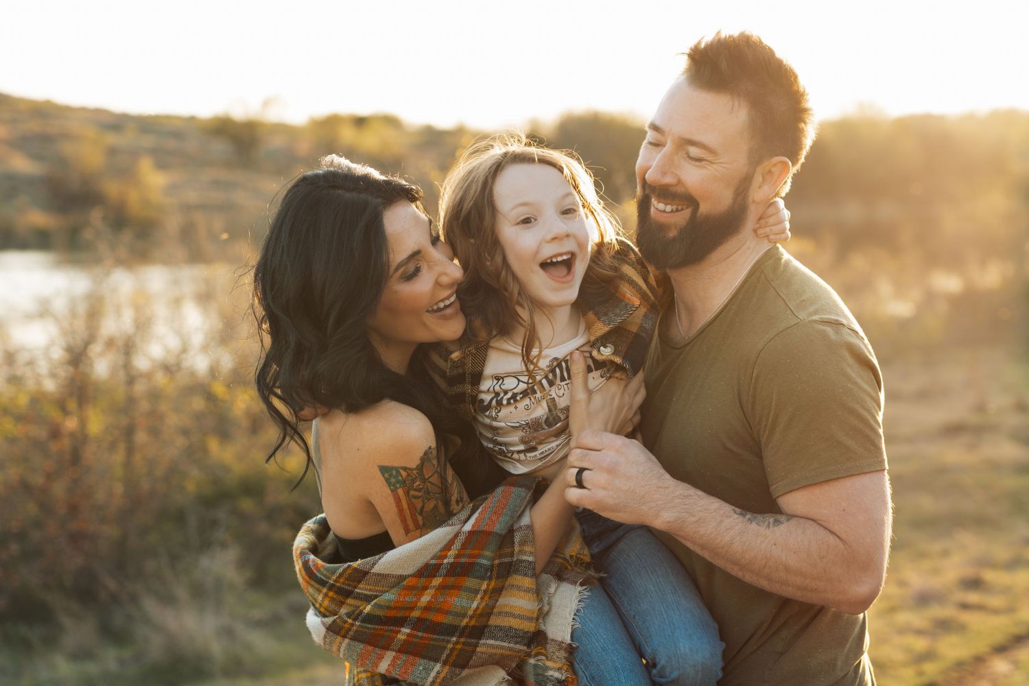 Family enjoying a tender moment together during golden hour sunset in an outdoor setting.