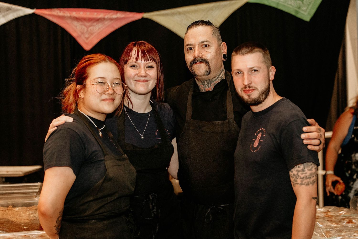 A group of people wearing black clothing pose together at what appears to be a social gathering or event.