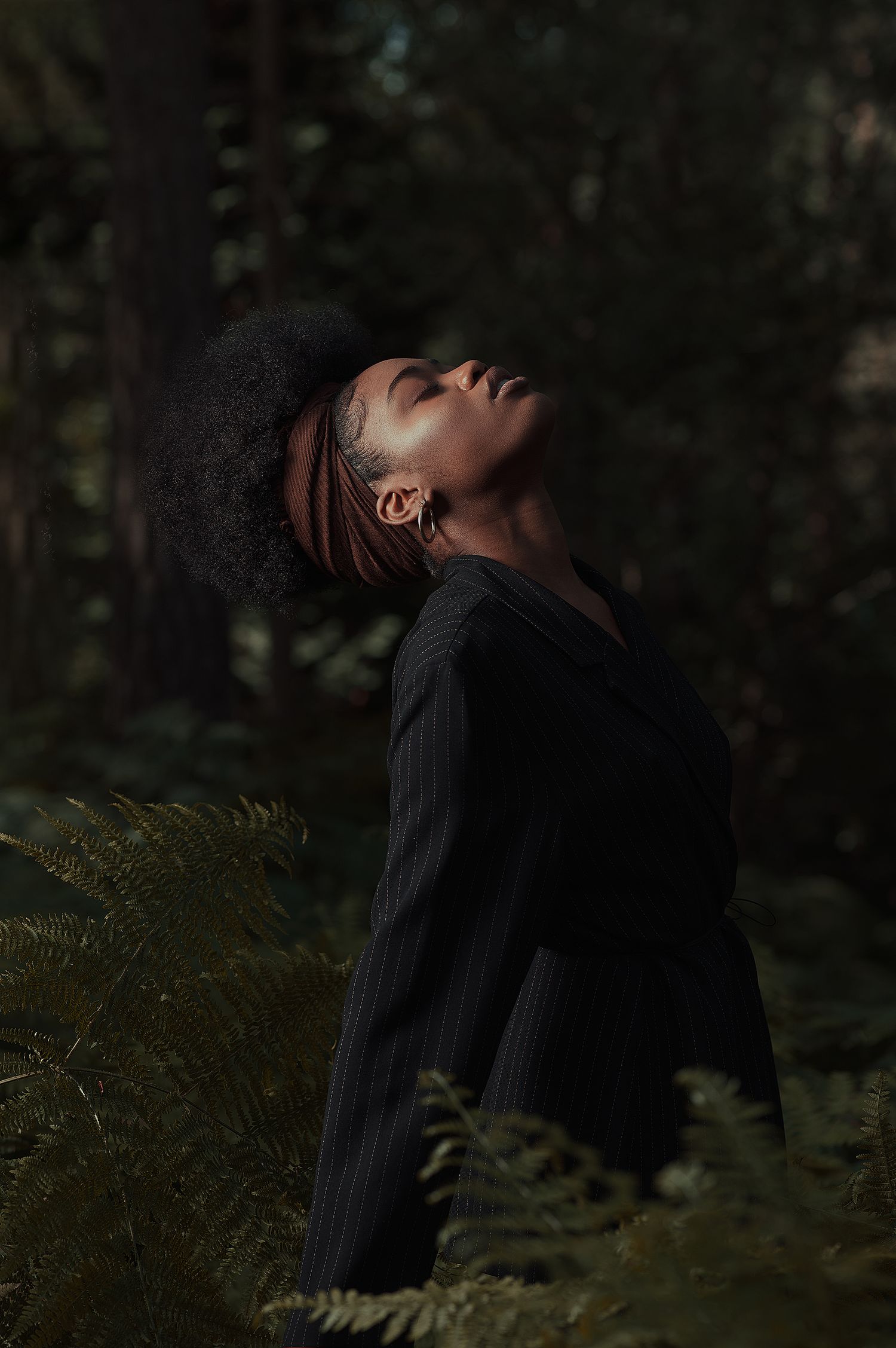 Dark moody portrait series in forest showing figure in black clothing against shadowy natural backdrop.