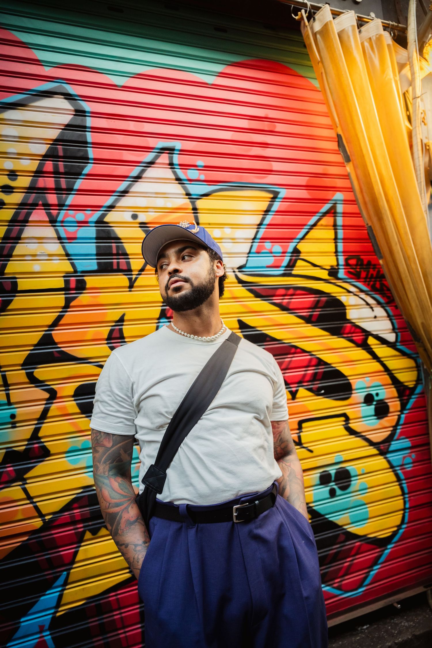 Urban fashion portrait against colorful graffiti wall with yellow and red metal shutters in background.