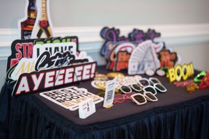 Party photo booth props and decorative signage displayed on a black-draped table at an event.