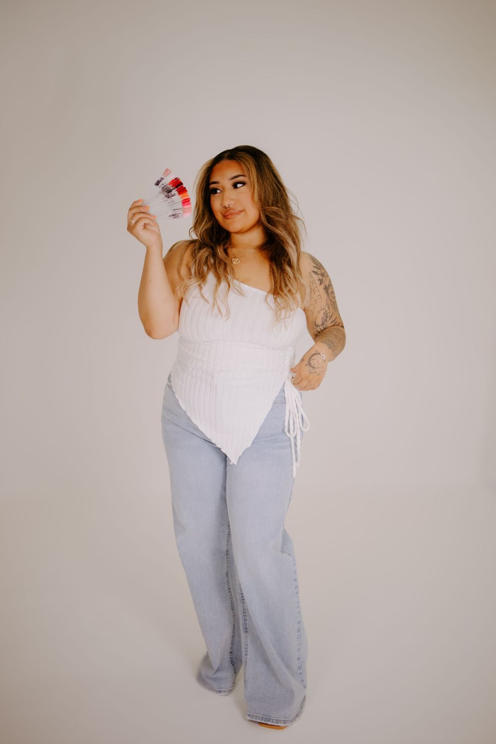 Full body shot in casual white top and light denim jeans against neutral background.