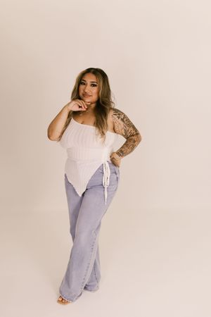 Model showcasing casual denim and white top ensemble in studio setting.