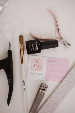 Beauty tools and accessories including nail clippers, brushes, and pink business cards on white surface.