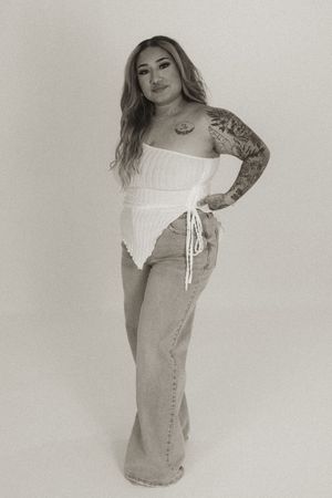 Fashion model in light denim dress and white top posing against neutral backdrop.