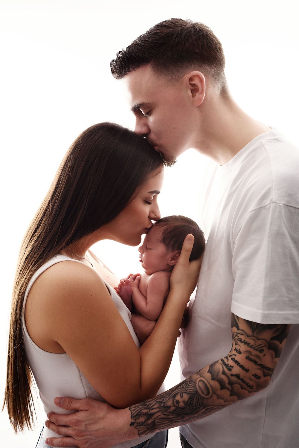 Intimate family portrait series in white showing tender moments with newborn.