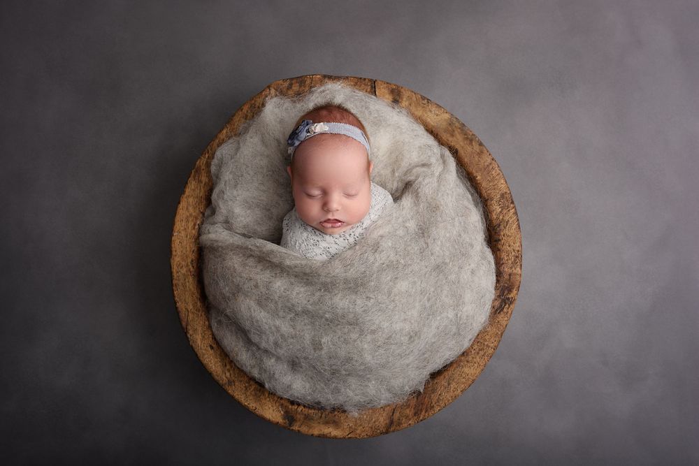 Collection of newborn portraits showing baby sleeping peacefully in wooden bowl against grey background.
