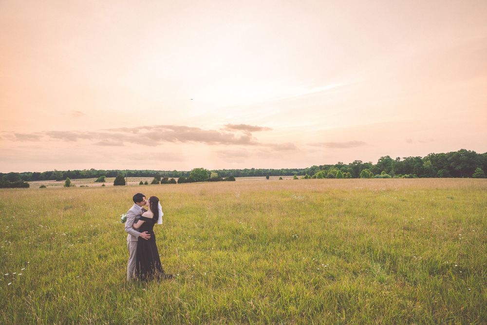 Couple embracing in a vast meadow during golden hour.